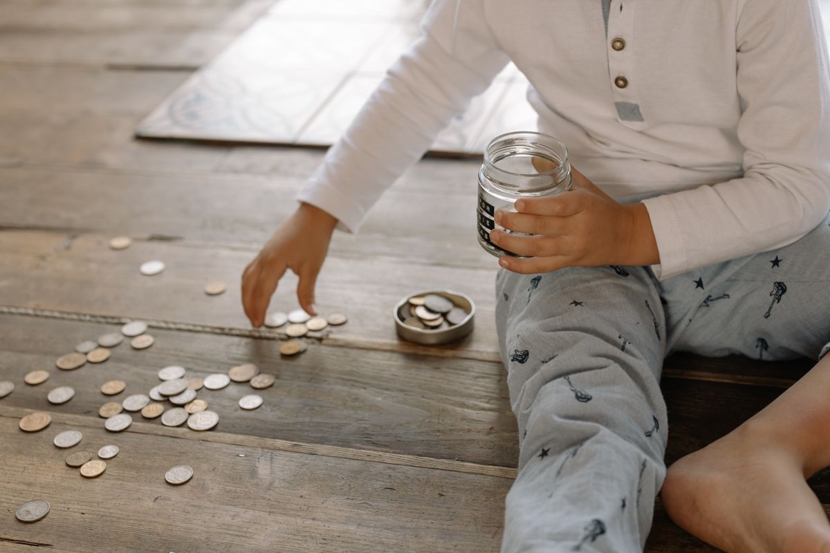 Un niño guarda monedas en un frasco para aprender el hábito del ahorro
